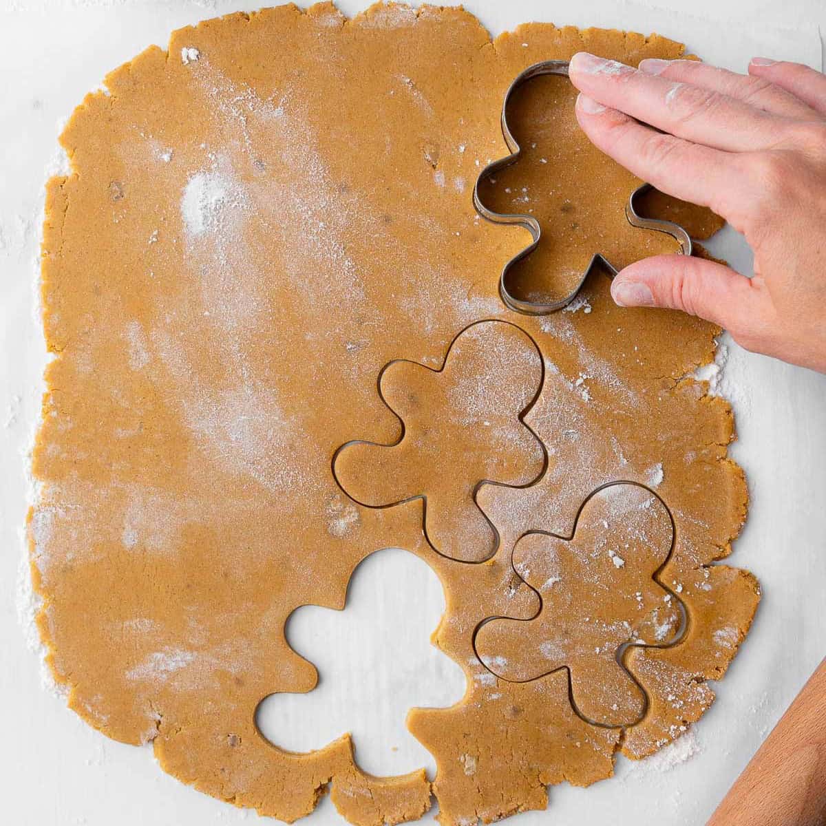 Using cookie cutters to cut out the gingerbread cookies.