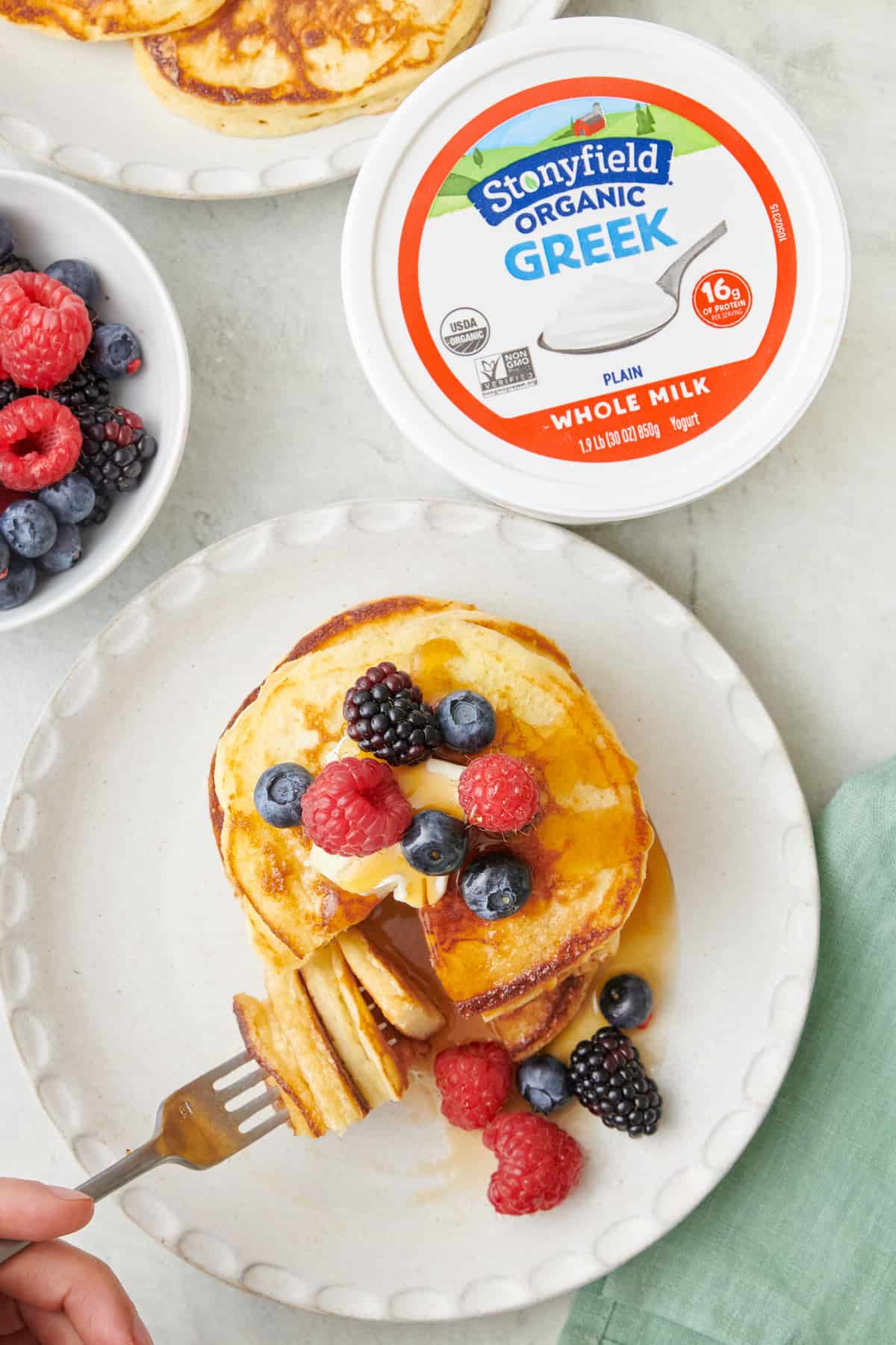 Fork lifting up a bite from a stack of pancakes made with Stonyfield Organic Greek Yogurt.