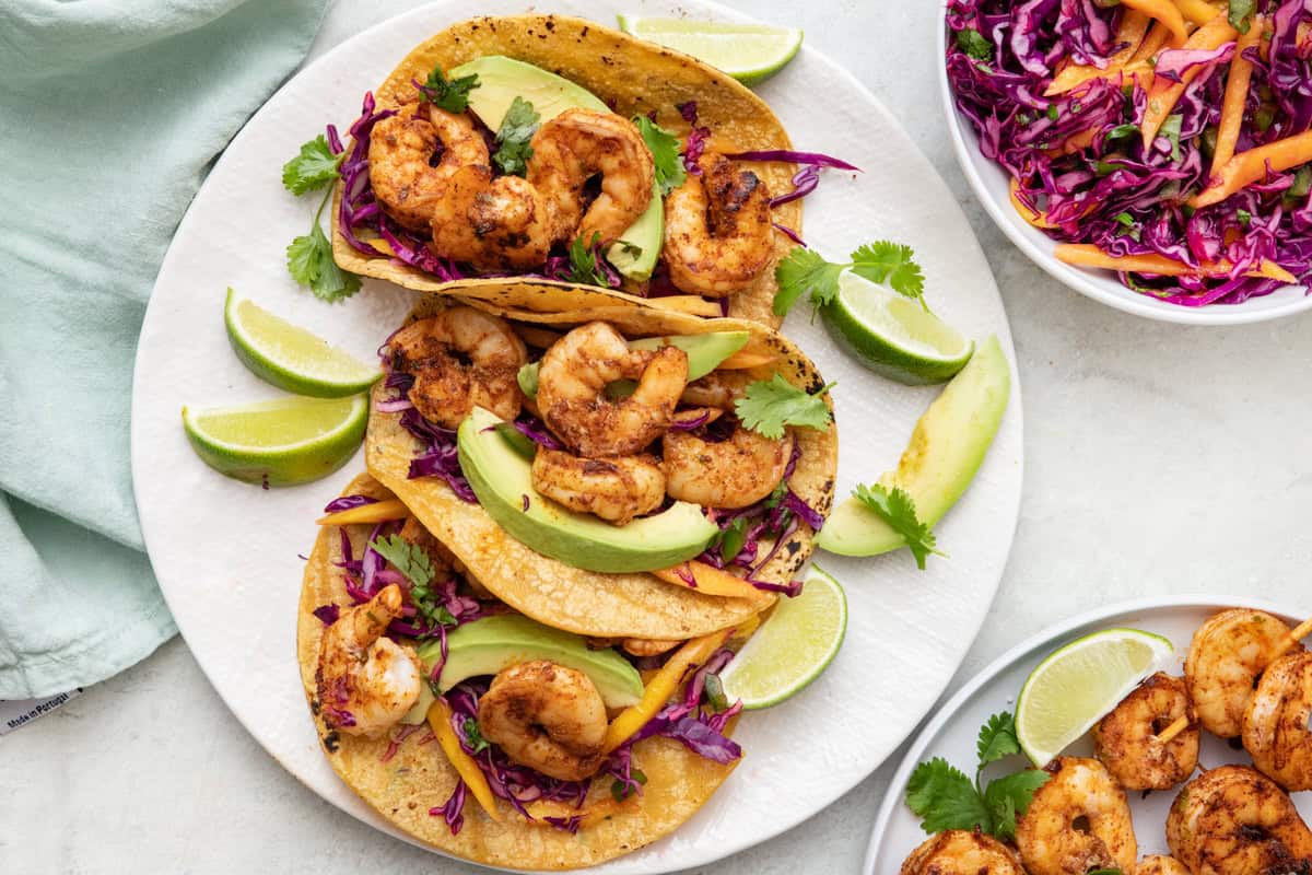 Best grilled shrimp tacos on corn tortillas with red cabbage slaw, limes and avocados.