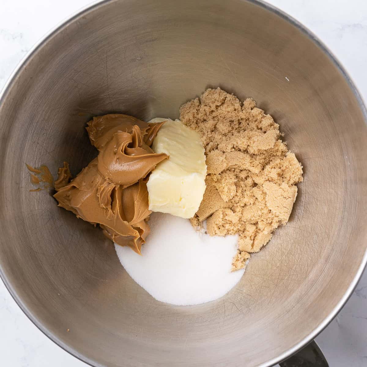 Butter, peanut butter, sugars in the bowl of a stand mixer before creaming together.