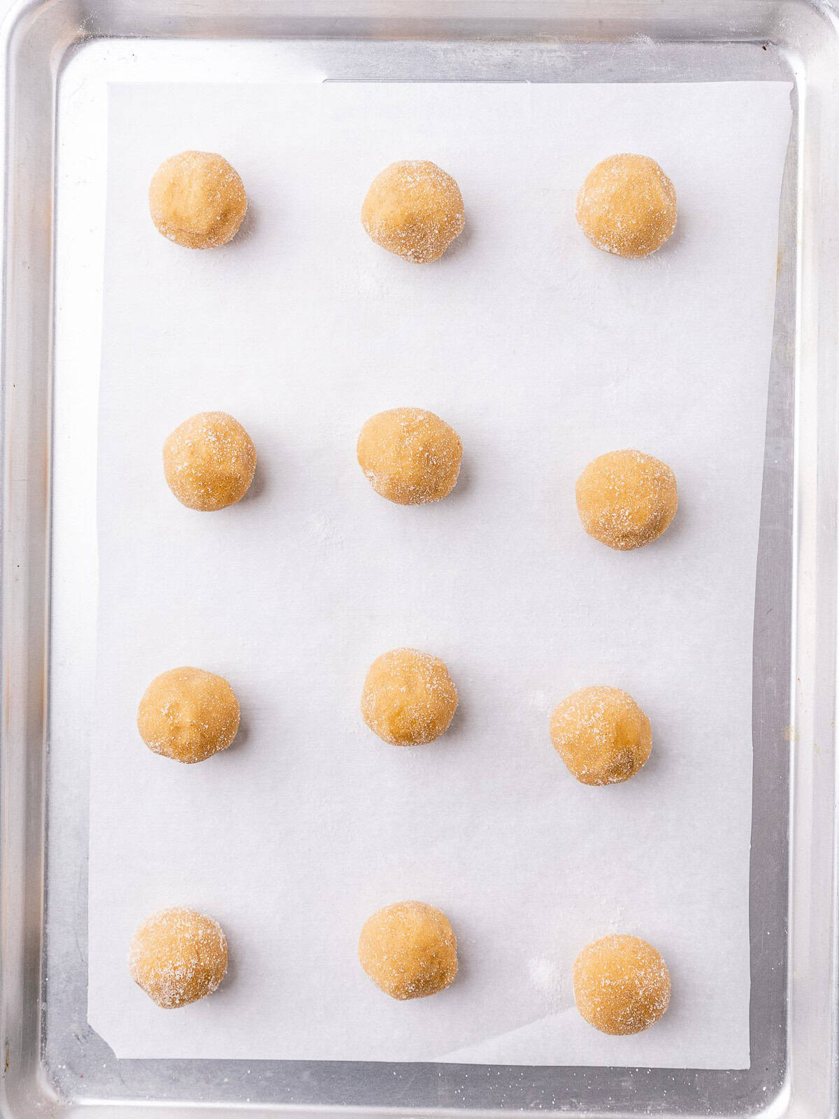 12 sugar coated dough balls on a baking sheet before baking.