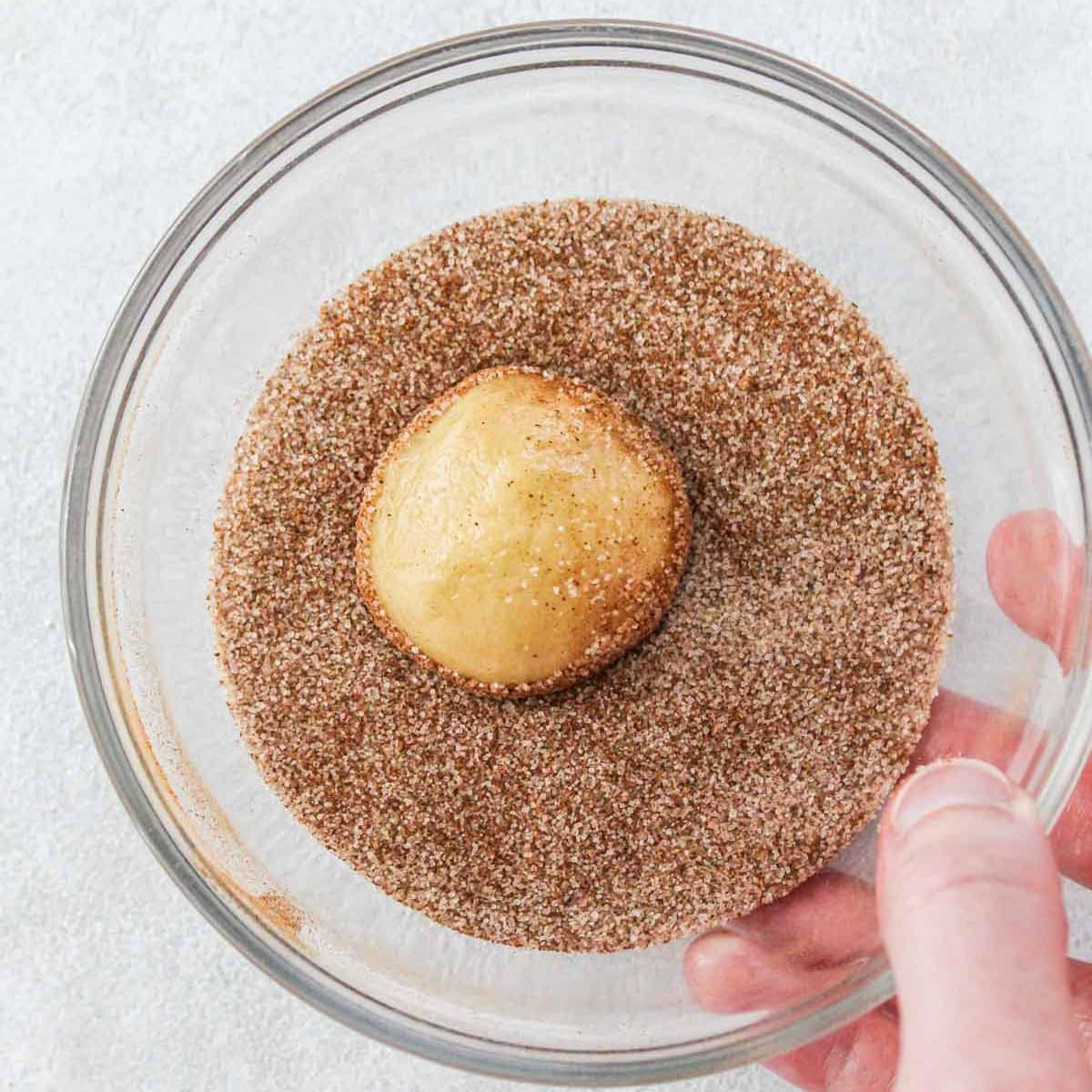 Rolling dough ball in sugar mixture.