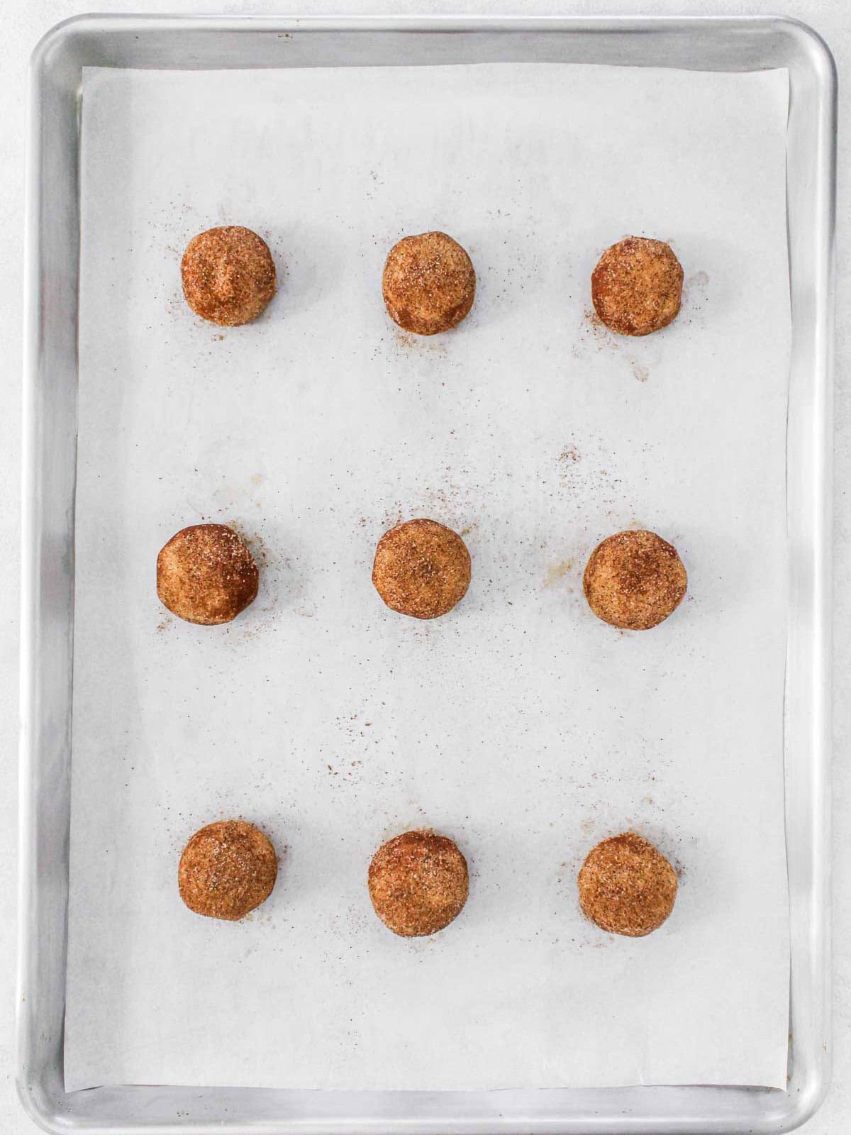 Coated cookie dough on a parchment lined cookie sheet before baking.
