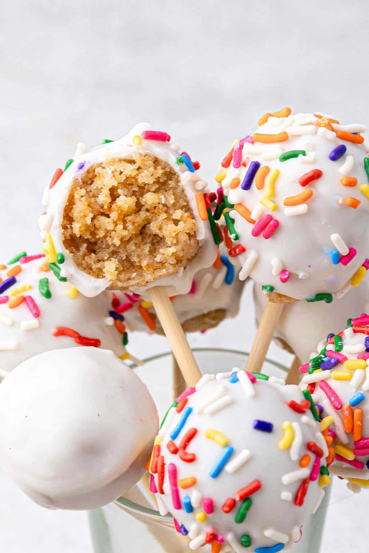 Close up on one cake pop with a bite taken out to show inside texture with more cake pops around.