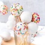 Cake pops in a glass, some decorated with sprinkles.