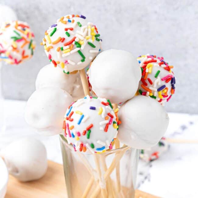 Cake pops in a glass, some decorated with sprinkles.