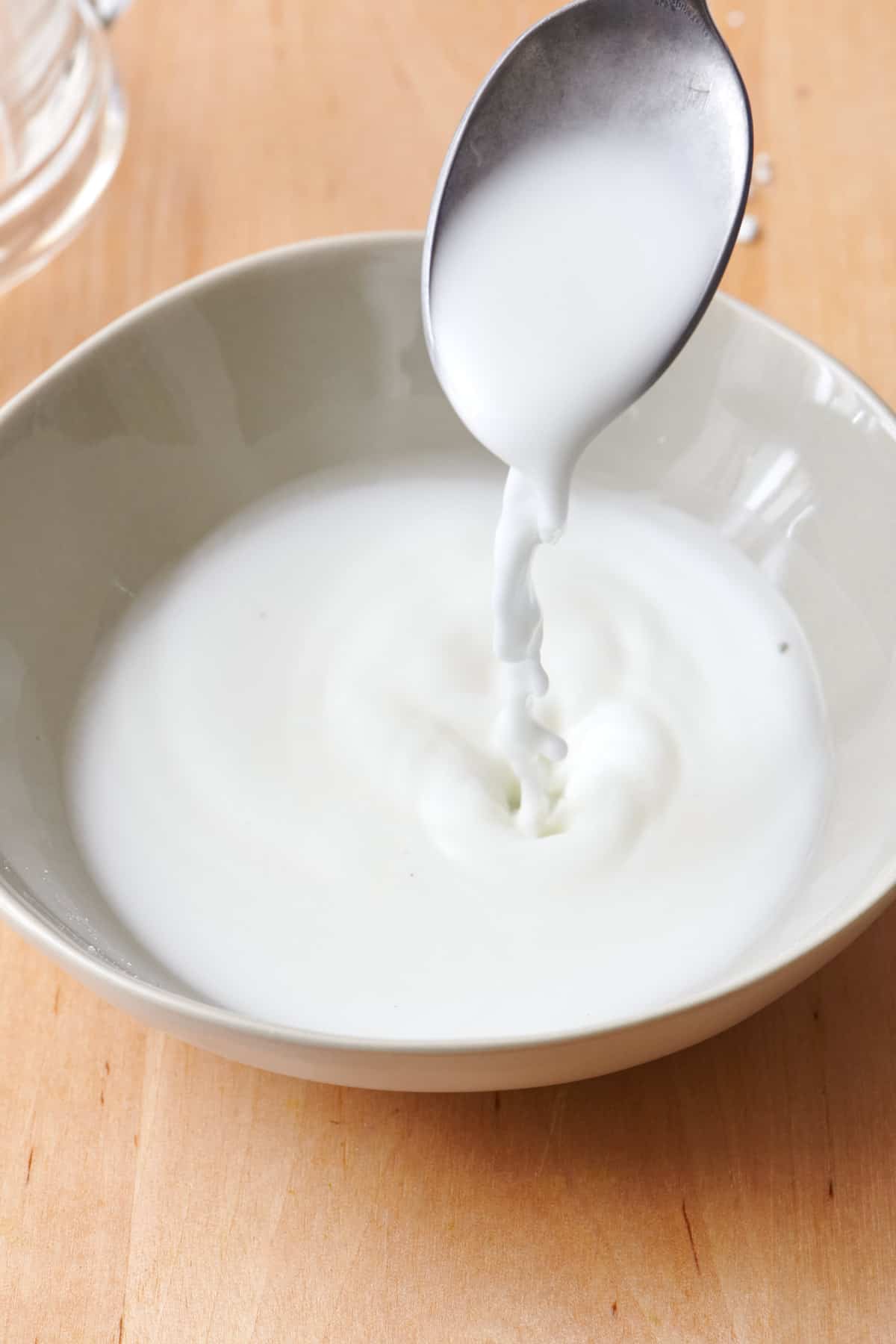 Spoon drizzling slurry into a bowl after being lifted up.
