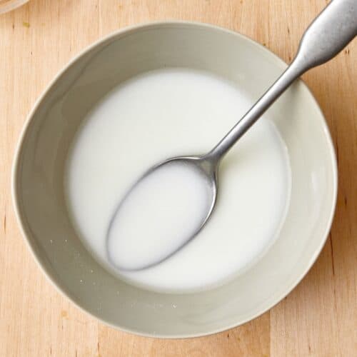 Cornstarch slurry in a bowl with a spoon dipped in.