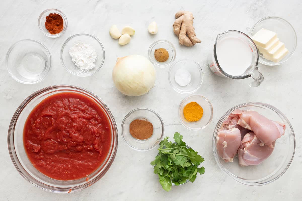Ingredients for recipe: cold water, cornstarch, paprika, garlic cloves, ginger, cumin, onion, salt, turmeric, crushed tomatoes, cilantro, coconut milk, butter, and chicken thighs.