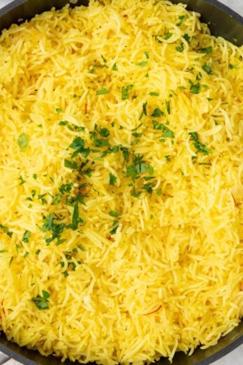 Square image of a pan of golden saffron rice.
