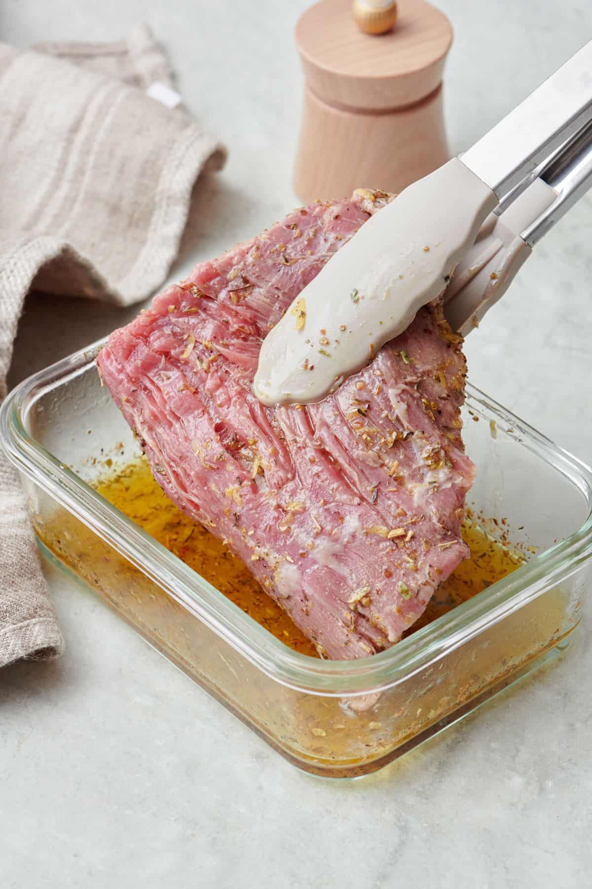 Tongs lifting steak out of marinade.