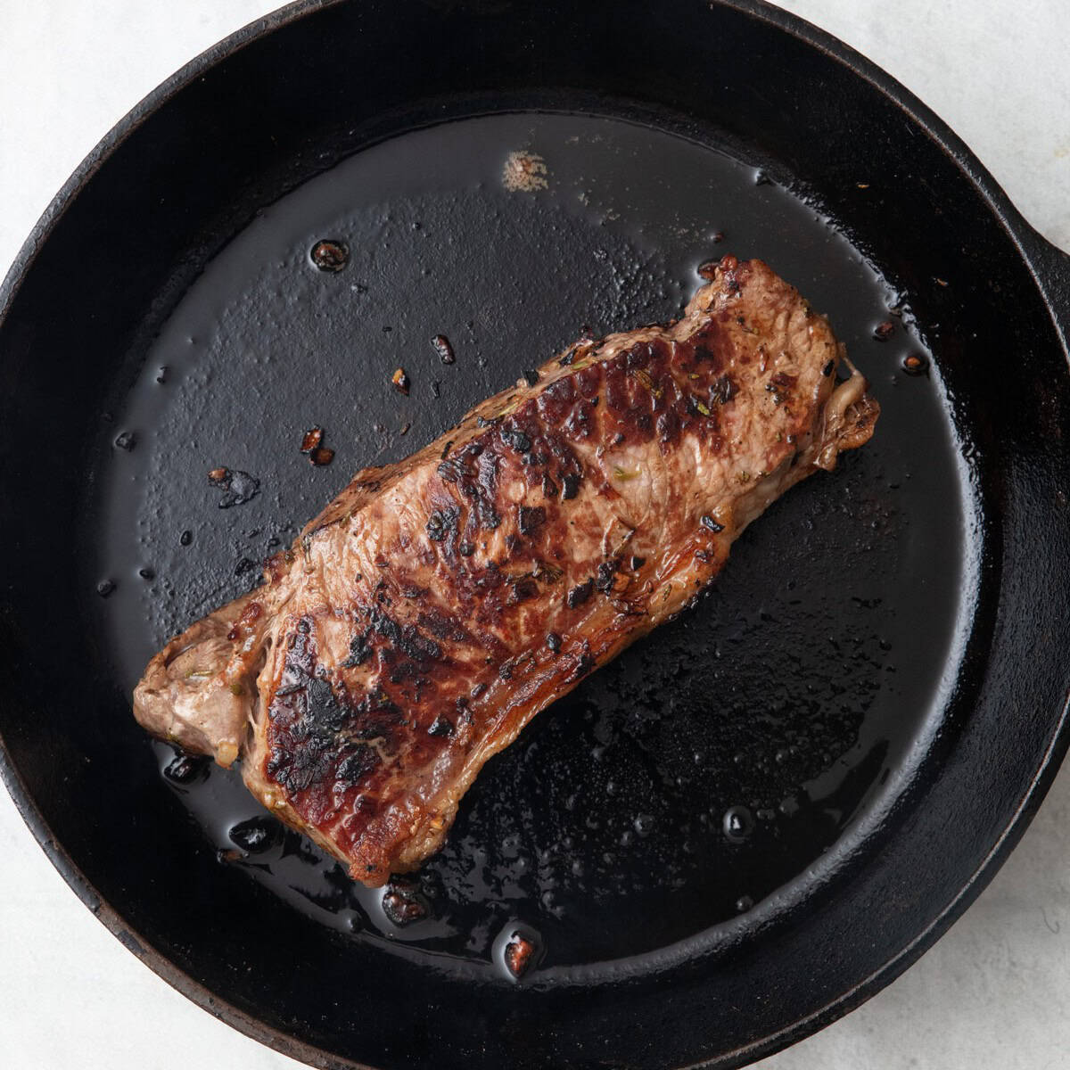 Flipped steak, showing one side cooked.