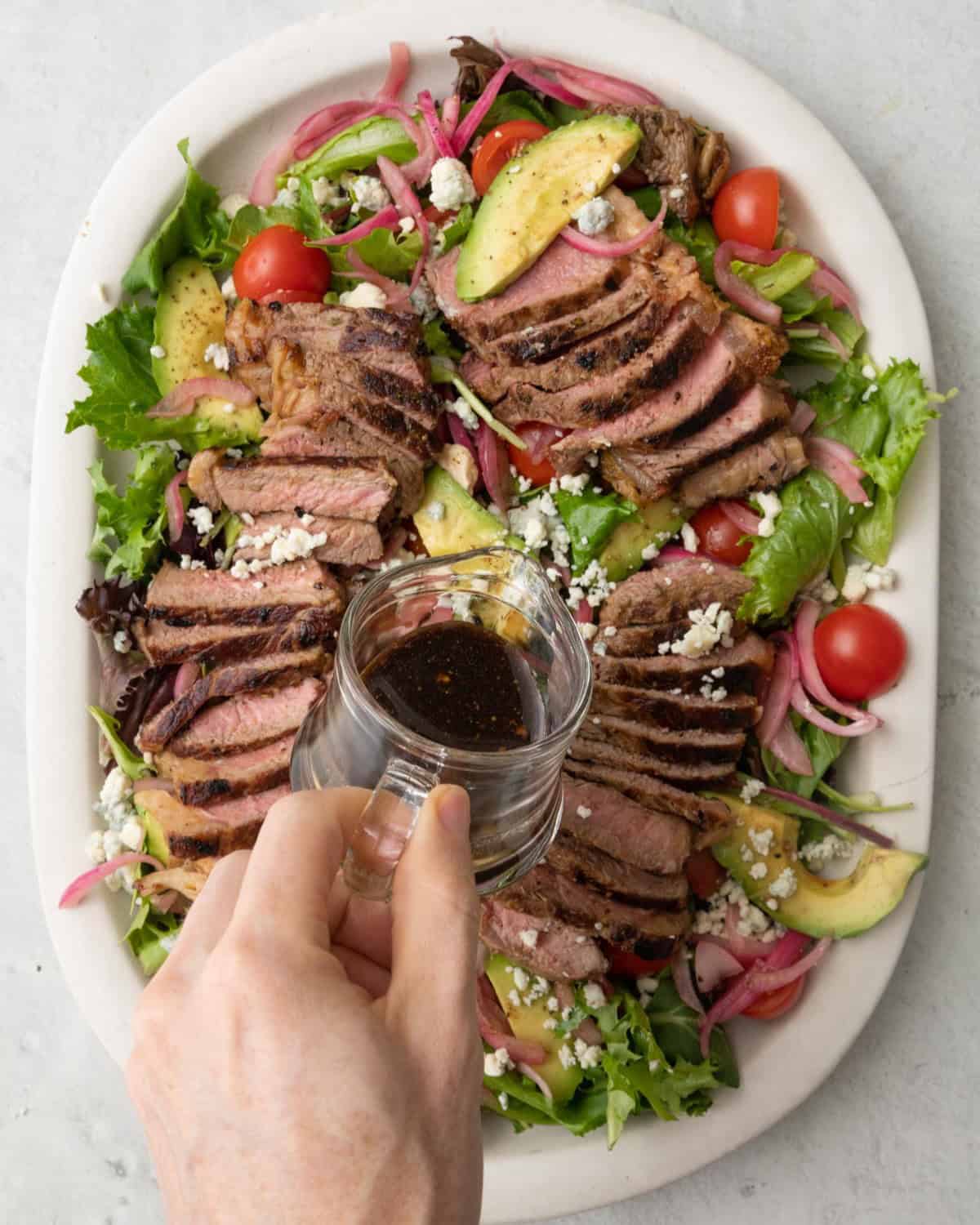 Pouring dressing over the salad.