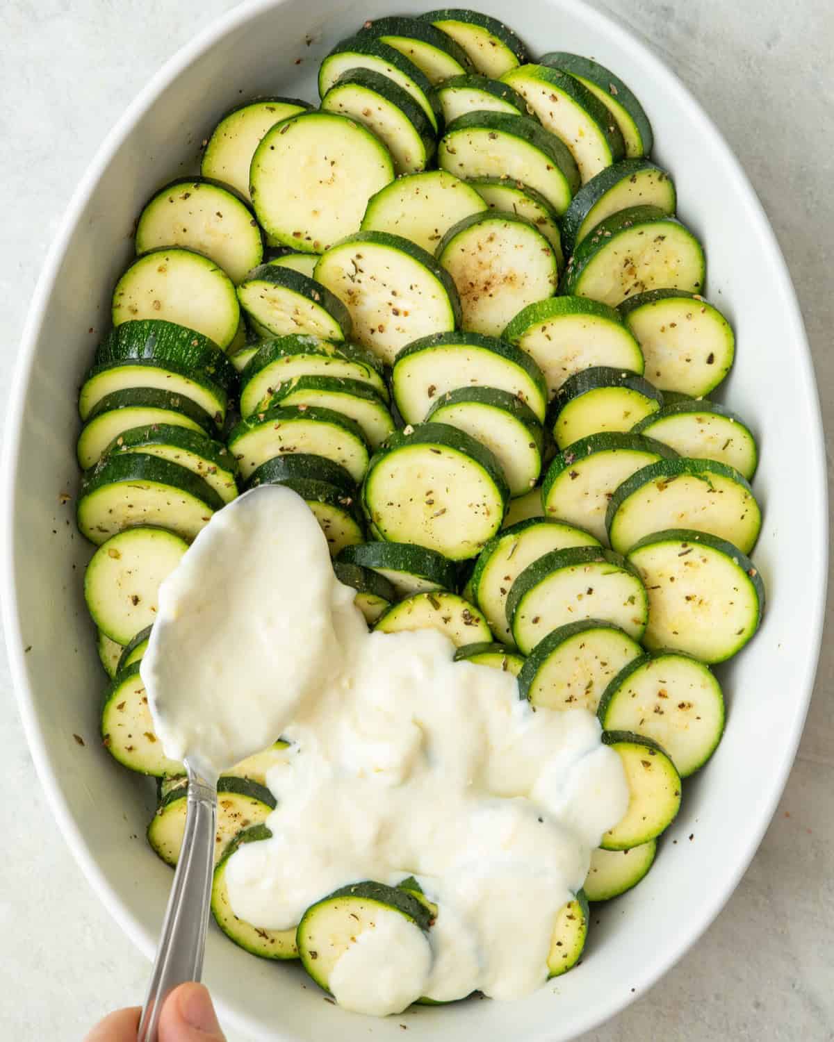 Pouring sauce over zucchini.
