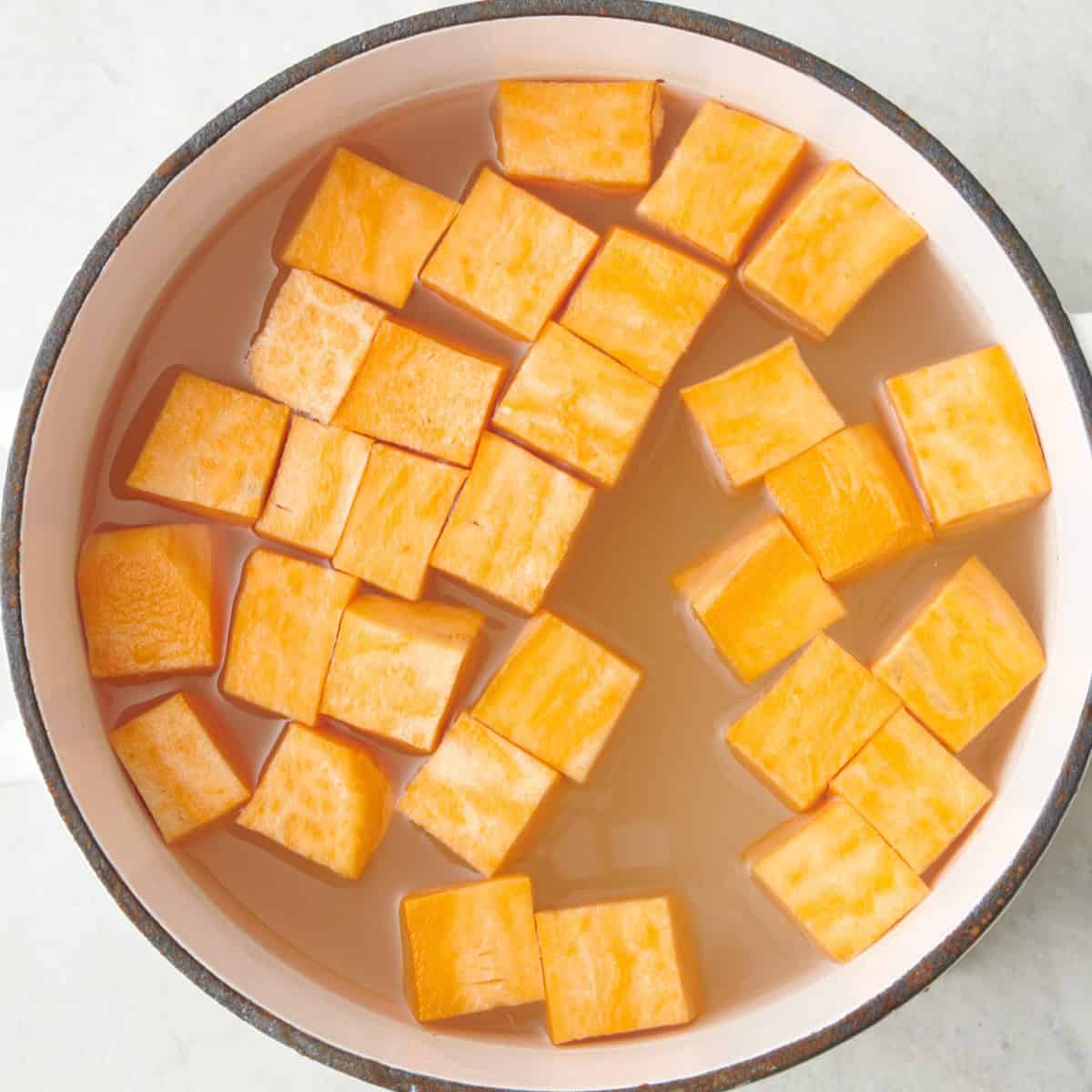 Peeled and cubed sweet potatoes in a pot of water before cooking.
