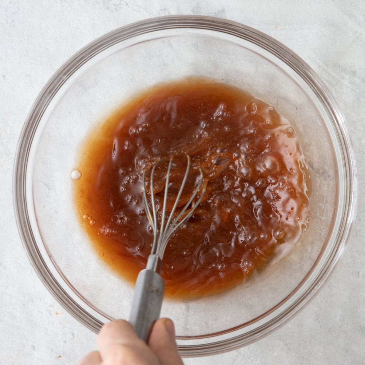 Whisking together the brown sugar, soy sauce, lime juice, sriracha, fish sauce, and water in a bowl.