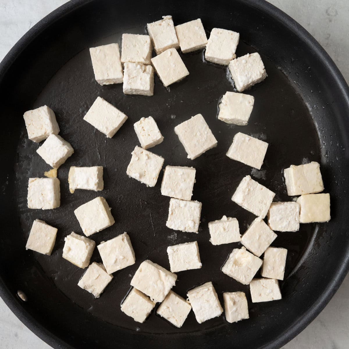 Cornstarch coated tofu cubes added to a hot wok with oil..