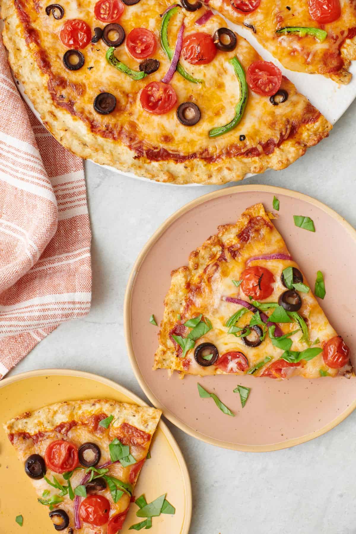 Chicken crust pizza with two plates, a slice on each.