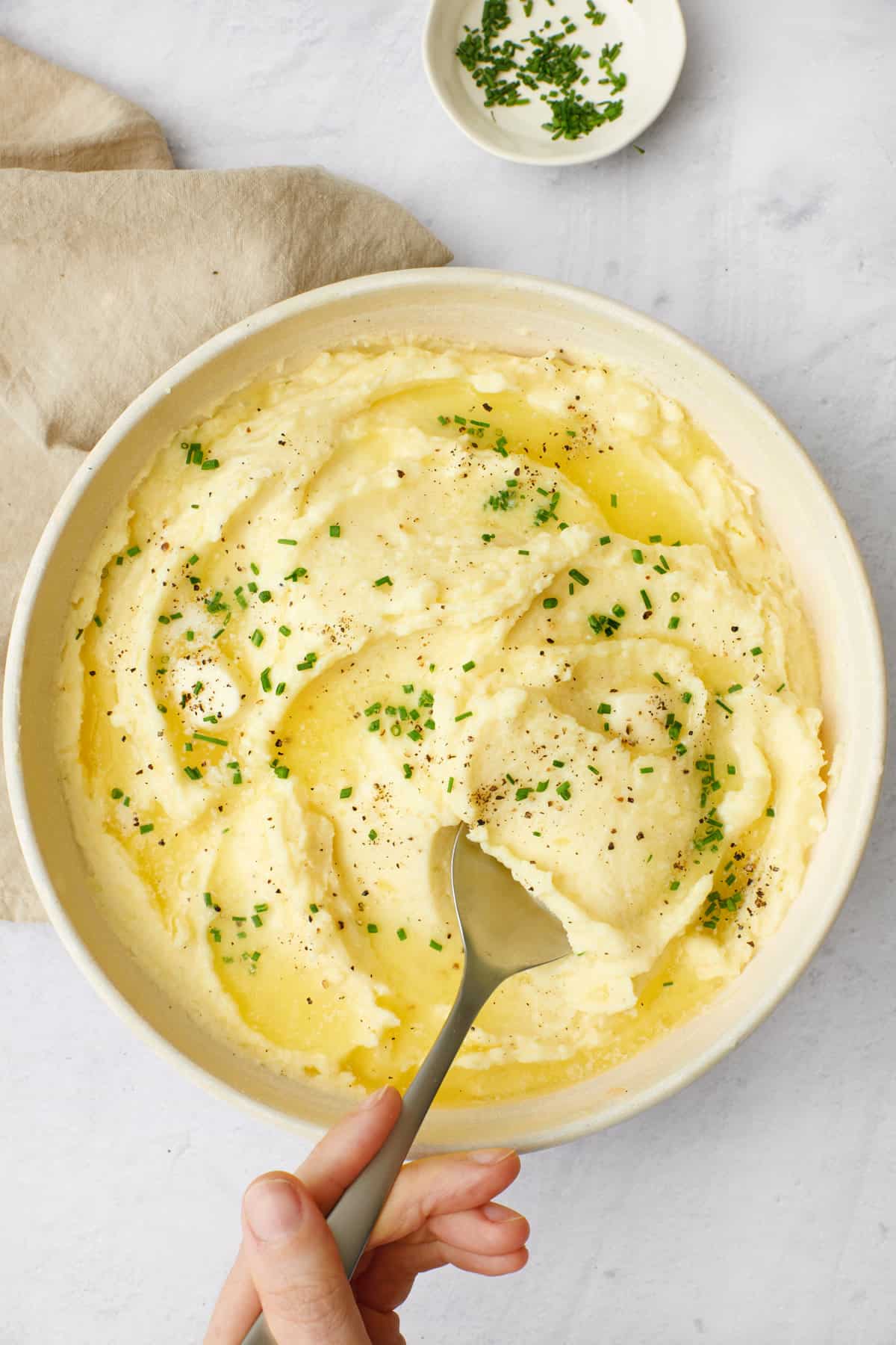 Spoon lifting up greek yogurt mashed potatoes from bowl.