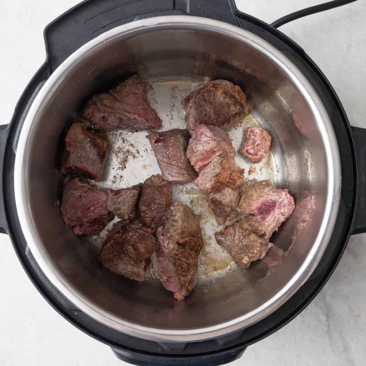 Beef added to Instant Pot, partially browned.