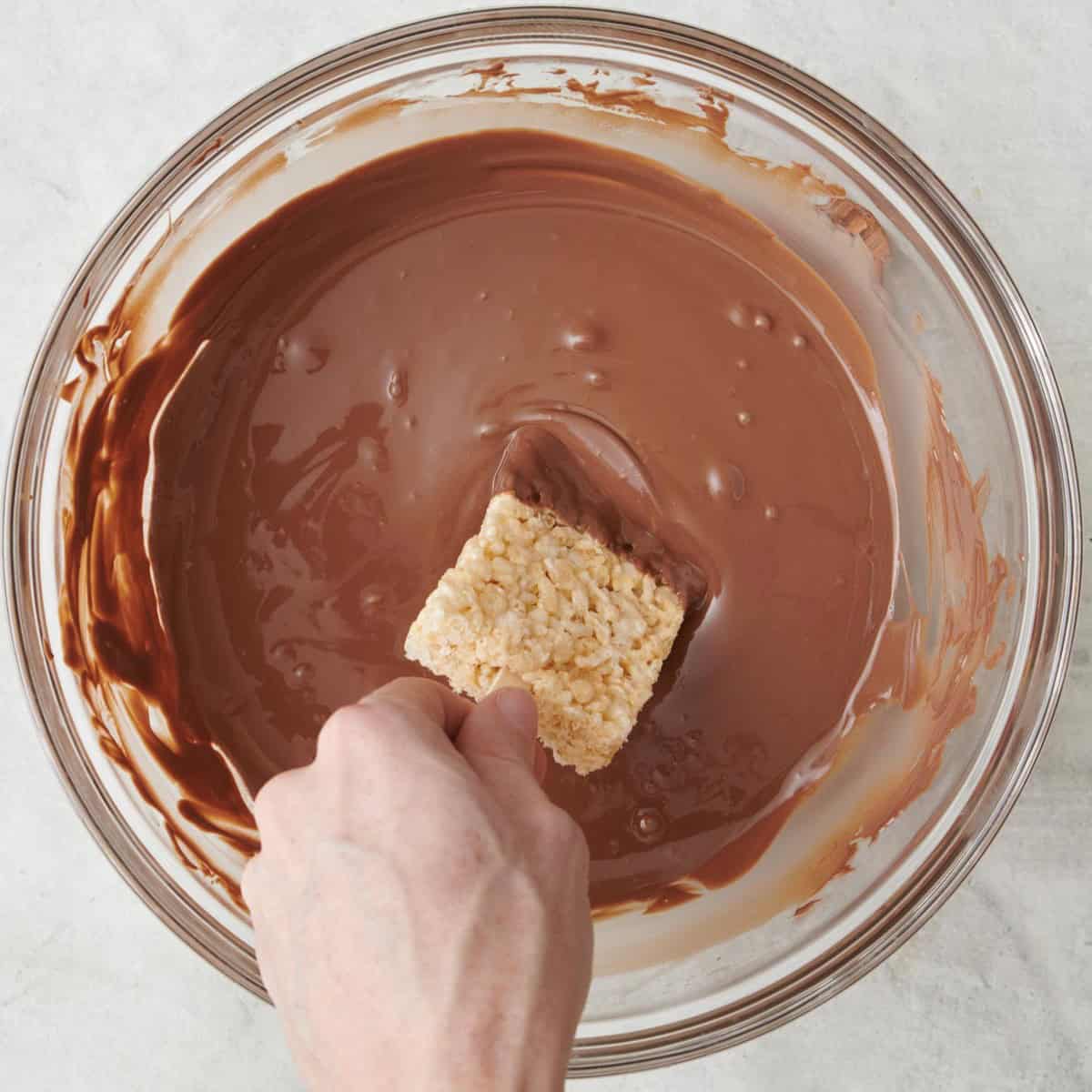 Rice krispie on a stick being dipped into candy melts.