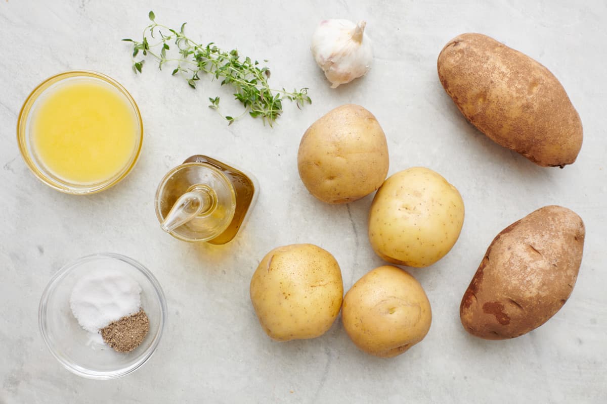 Ingredients for recipe: melted butter, oil, thyme, slat and pepper, garlic, and two types of potatoes.