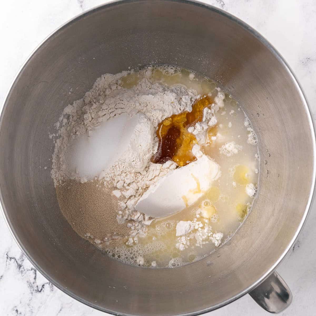 2 cups of flour, water, honey, oil, yeast, and salt in the bowl of a stand mixer before combining.