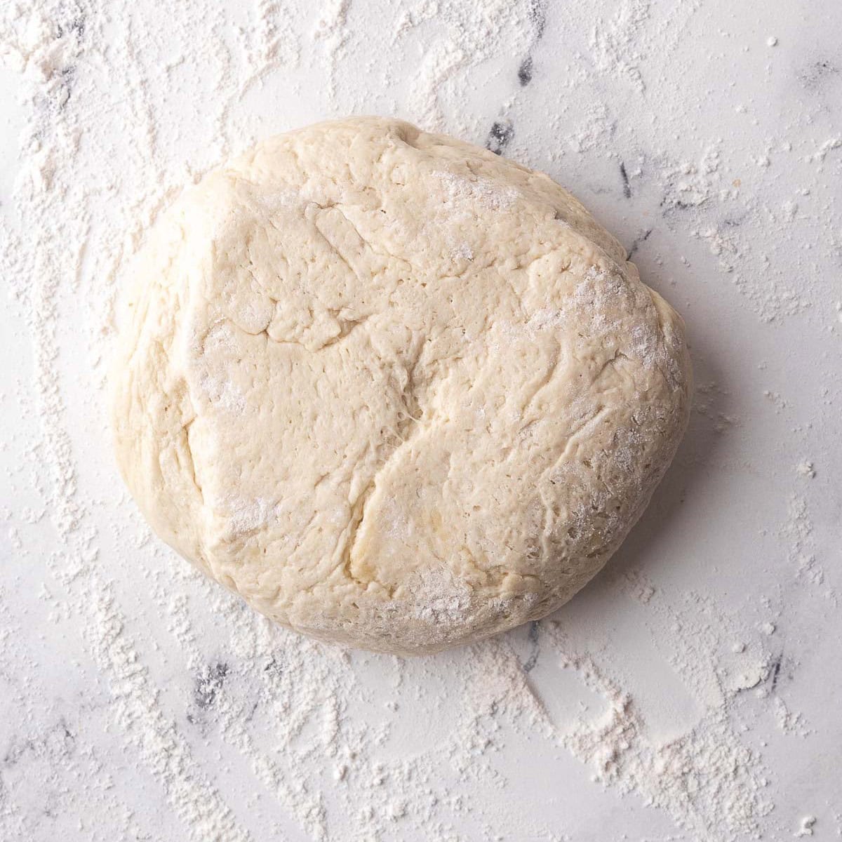 Deflated dough transferred to a work surface with flour underneath.