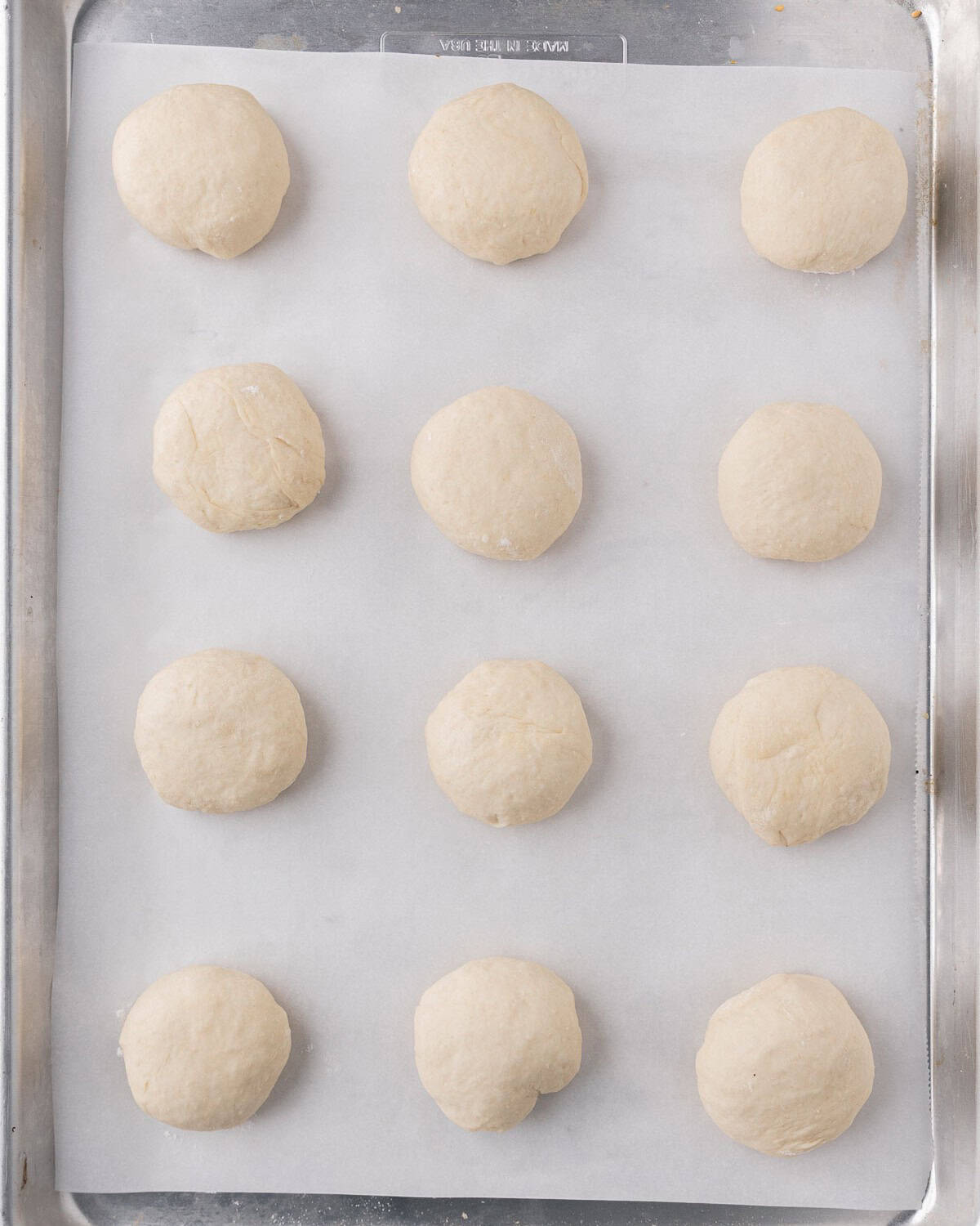 Dough balls on a parchment lined baking sheet before the second rise