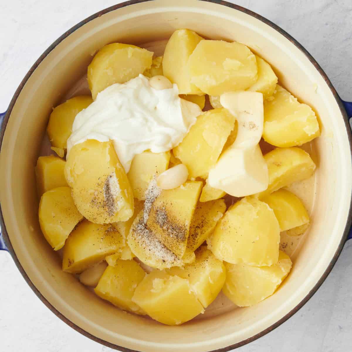 Cooked potatoes returned to pot with yogurt, butter and seasoning added.