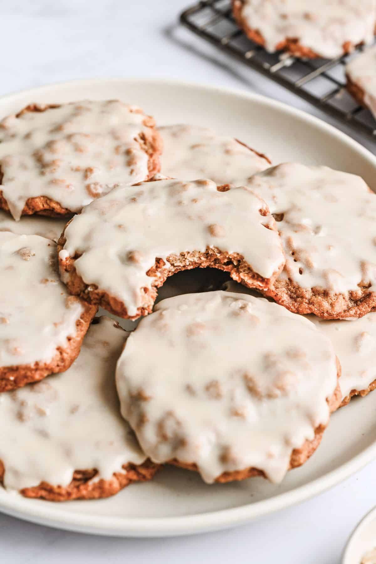 Plate of iced oatmeal cookies with a bite taken out of one.