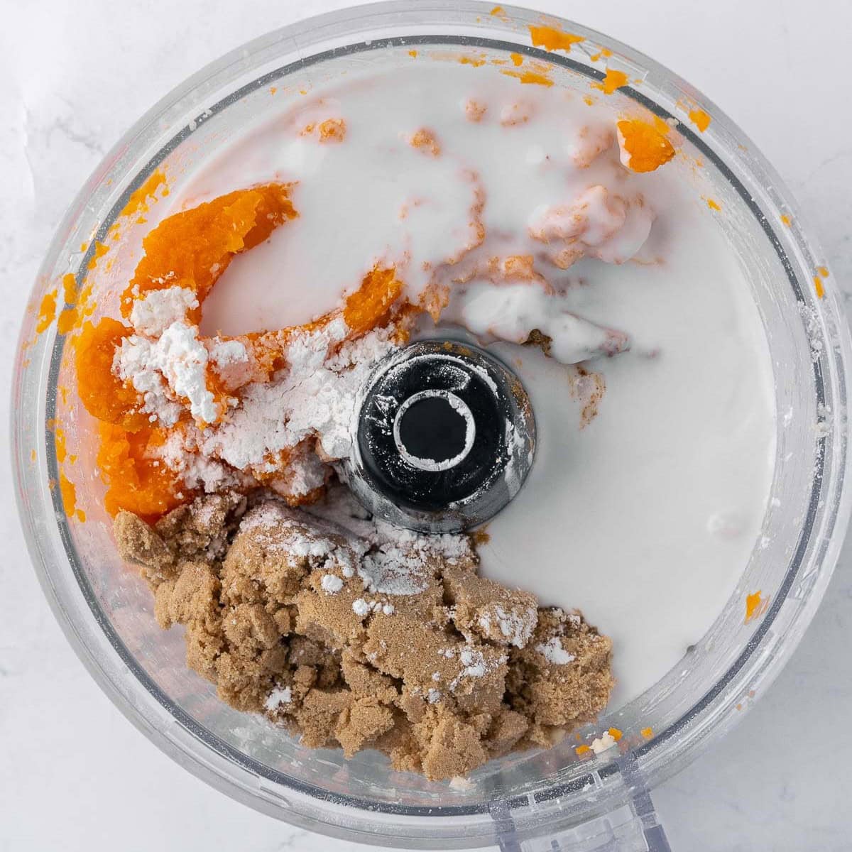 Cooked sweet potatoes and remaining pie filling ingredients in the bowl of food processor combing.
