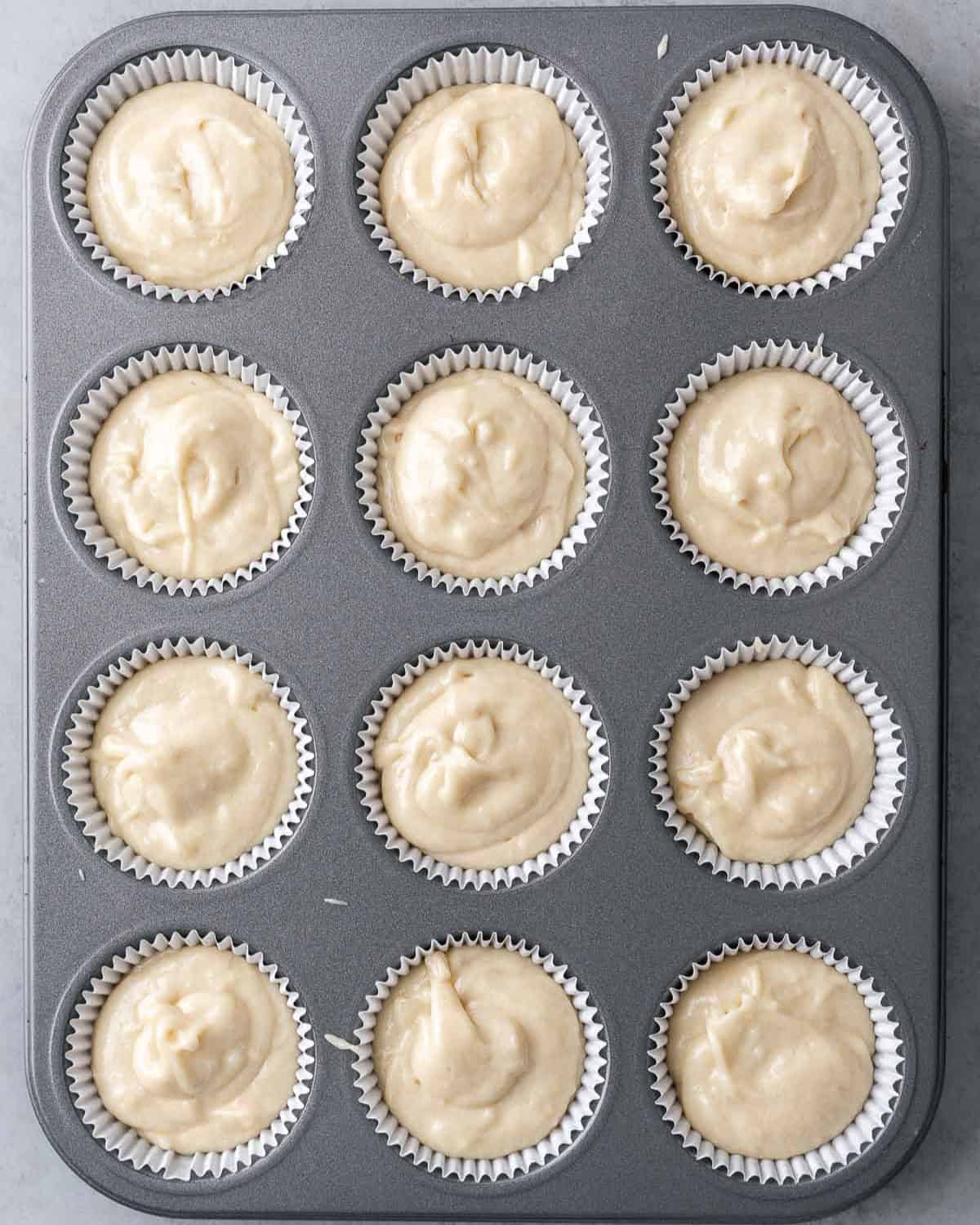 Cupcake batter divided into a 12 cup lined pan before baking.