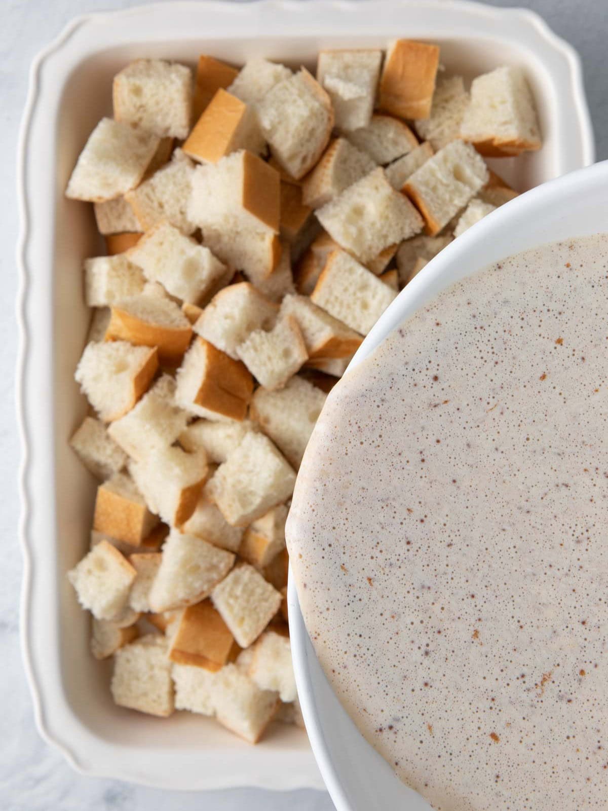 Pouring batter over french toast cubes.