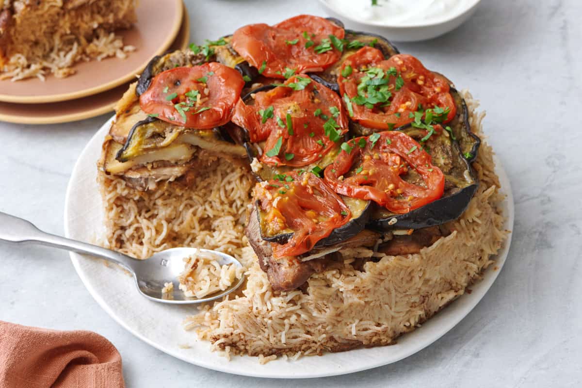 Maqluba on a serving plate with a serving removed nearby.