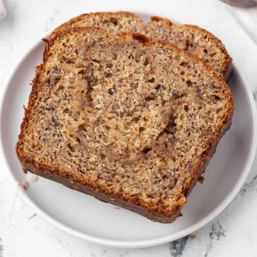 Closeup of 2 pieces of cinnamon swirl banana bread on a white plate.
