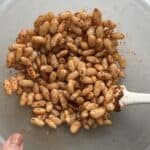 Cooked white beans getting tossed in seasoning before air fried
