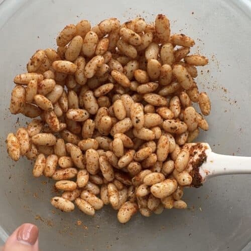 Cooked white beans getting tossed in seasoning before air fried