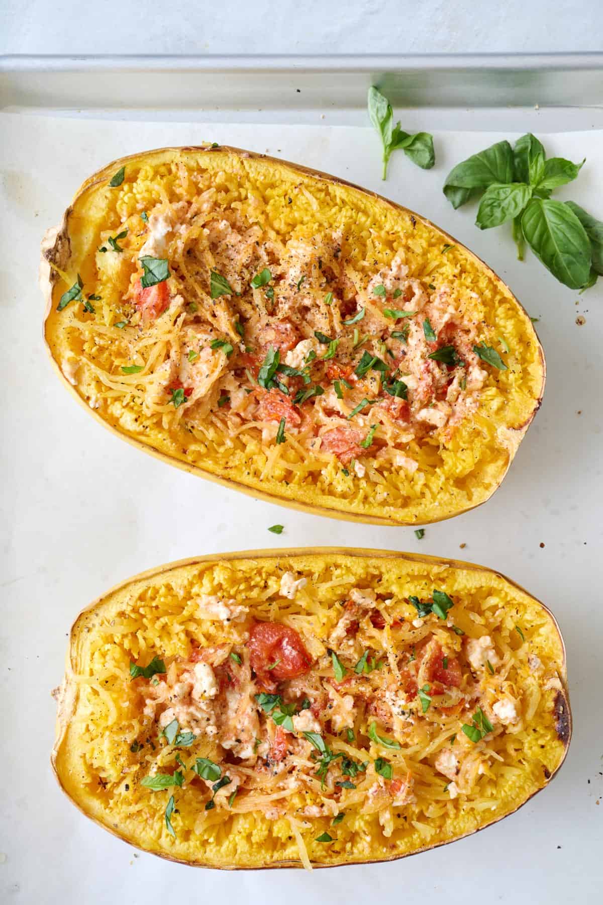 Two feta spaghetti squashes baked on parchment paper.