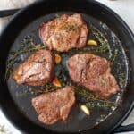 Filet mignon cooked in a cast iron skillet with butter, garlic, and fresh thyme.
