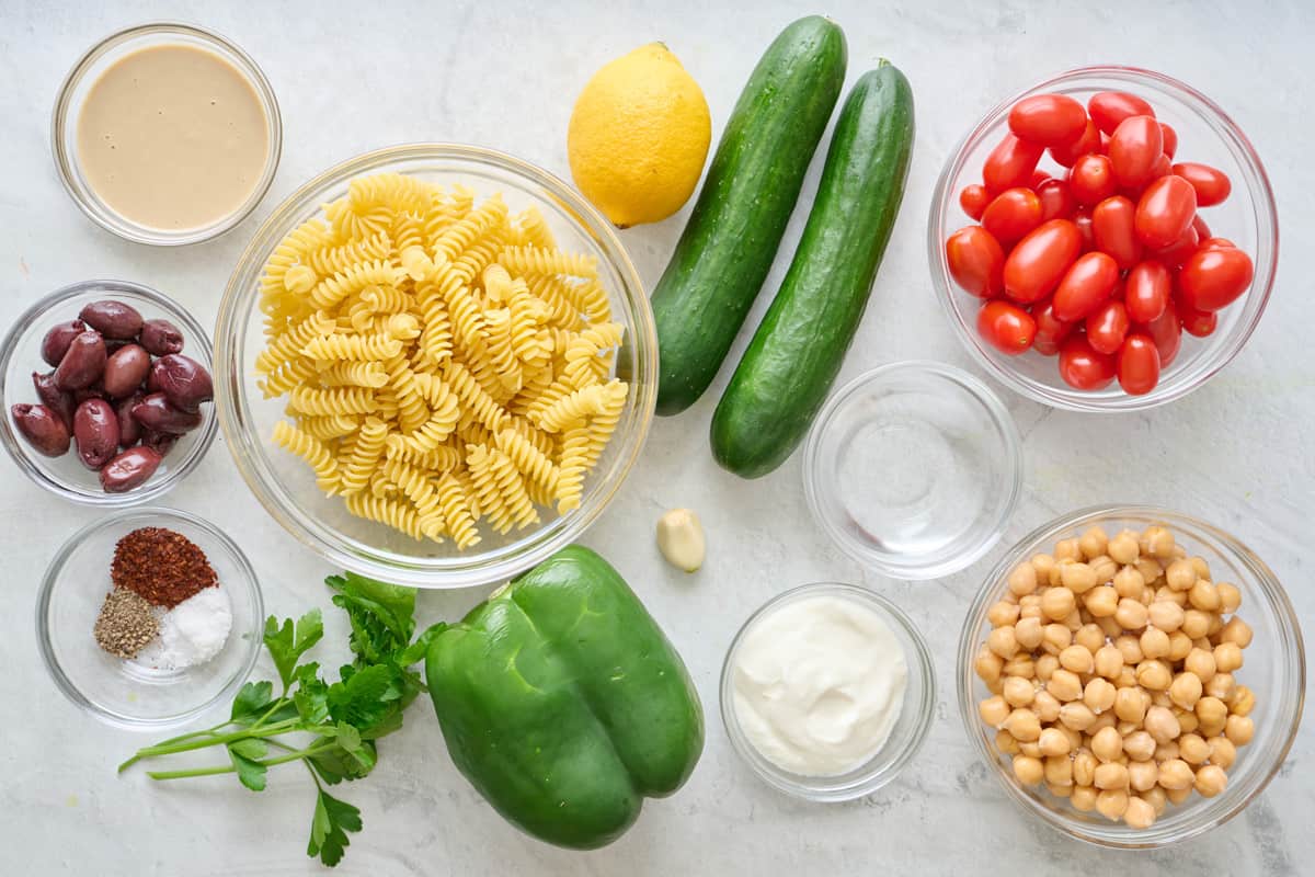 Ingredients to make recipe: Rotini pasta, chickpeas, cucumbers, bell pepper, grape tomatoes, kalamata olives, fresh parsley, tahini, lemon, garlic, water, Greek yogurt, sumac, salt, and black pepper.