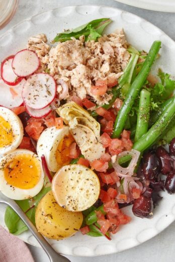 Tuna nicoise salad on a small plate with a fork.