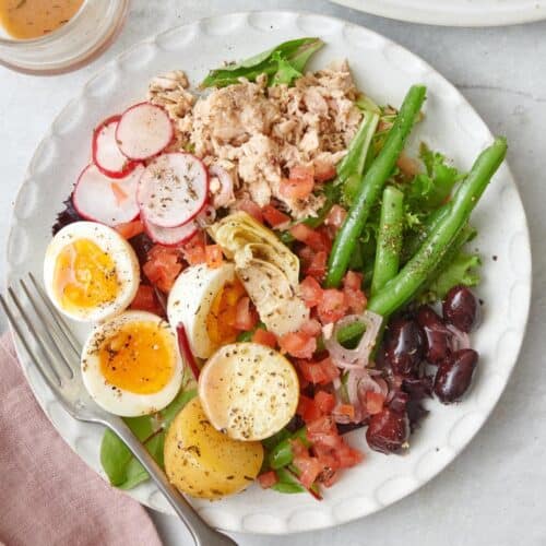 Tuna nicoise salad on a small plate with a fork.