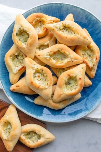 Serving bowl full of homemade cheese fatayer with a few off to the side.