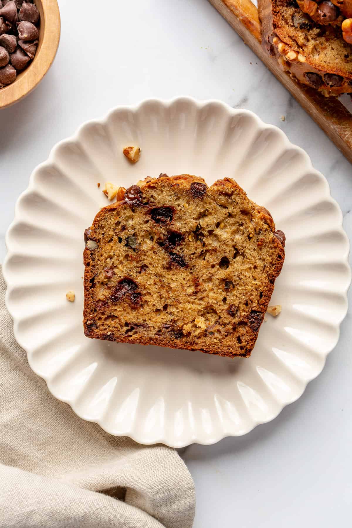 Slice of banana bread with chocolate chips and walnuts on a plate.