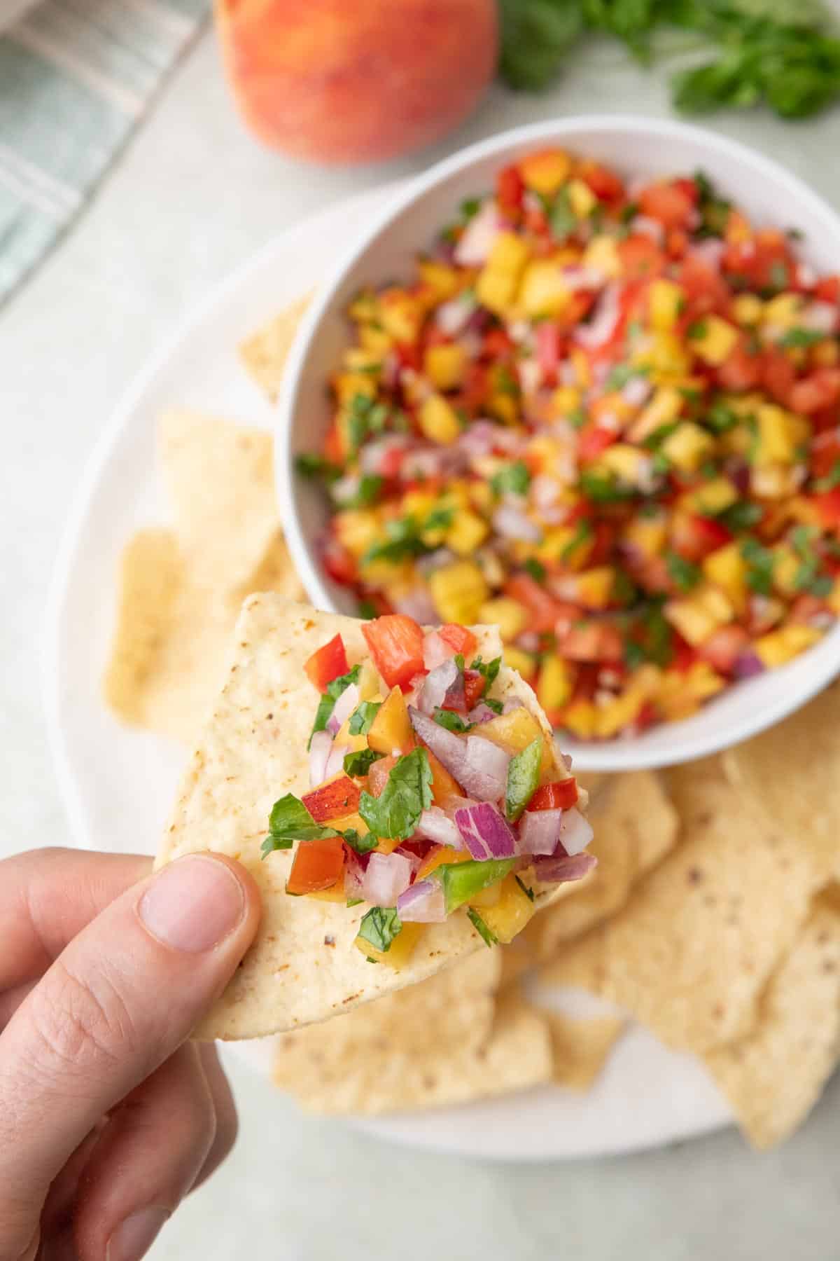 Bite of peach salsa on a tortilla chip.