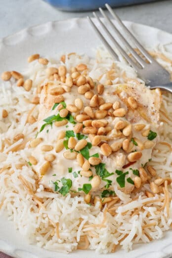 Closeup of samke harra on a small plate over Lebanese rice with pine nuts and parsley on top.
