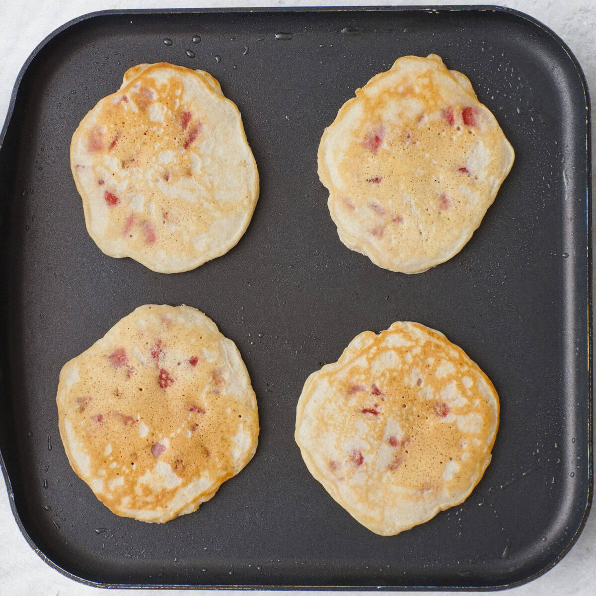 Four cooked pancakes on a pan.
