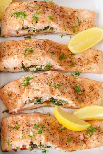 Stuffed baked salmon in a white baking dish garnished with lemon slices.