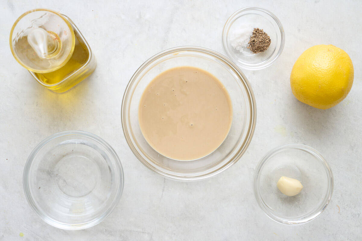 Ingredients for recipe in individual containers: oil, water, tahini, salt and pepper, lemon, garlic.